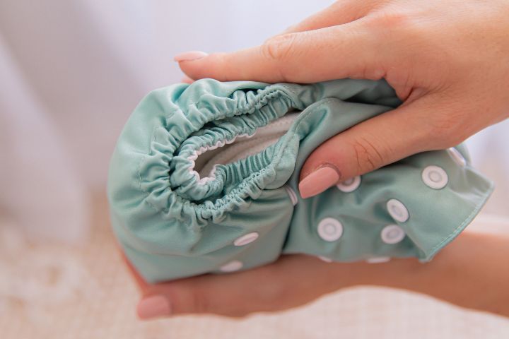Hands holding a double gusset sage green cloth nappy