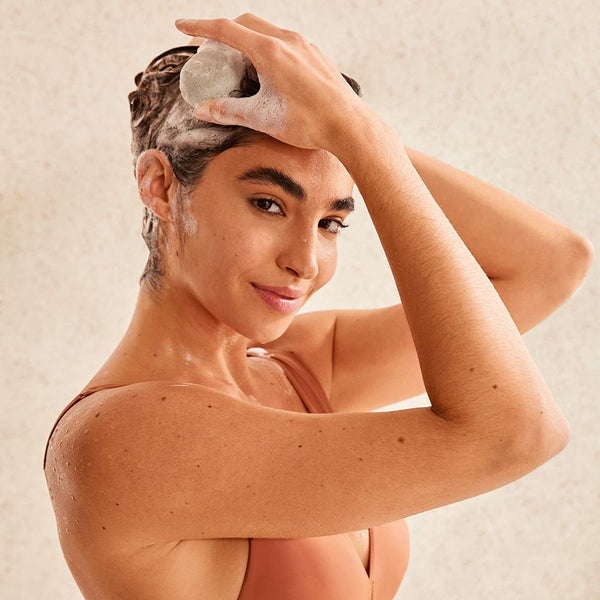 Girl applying shampoo bar on her hair