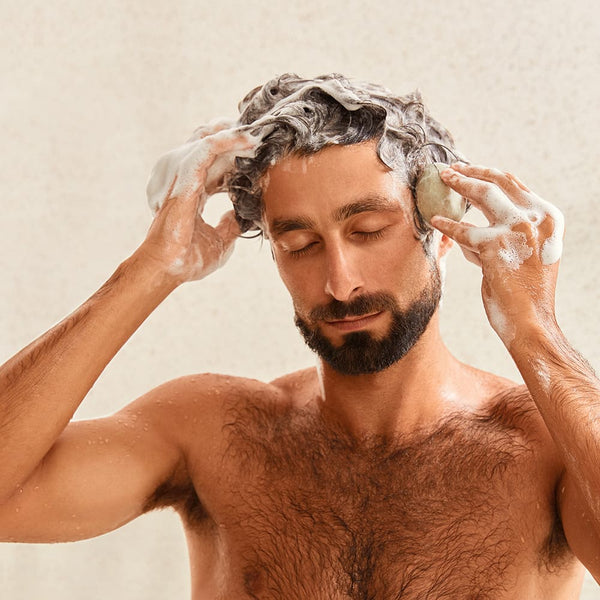 Man applying shampoo bar on his hair