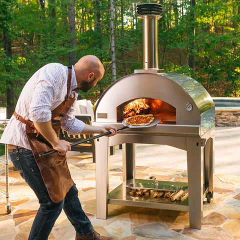Man loading a pizza into a wood fired oven