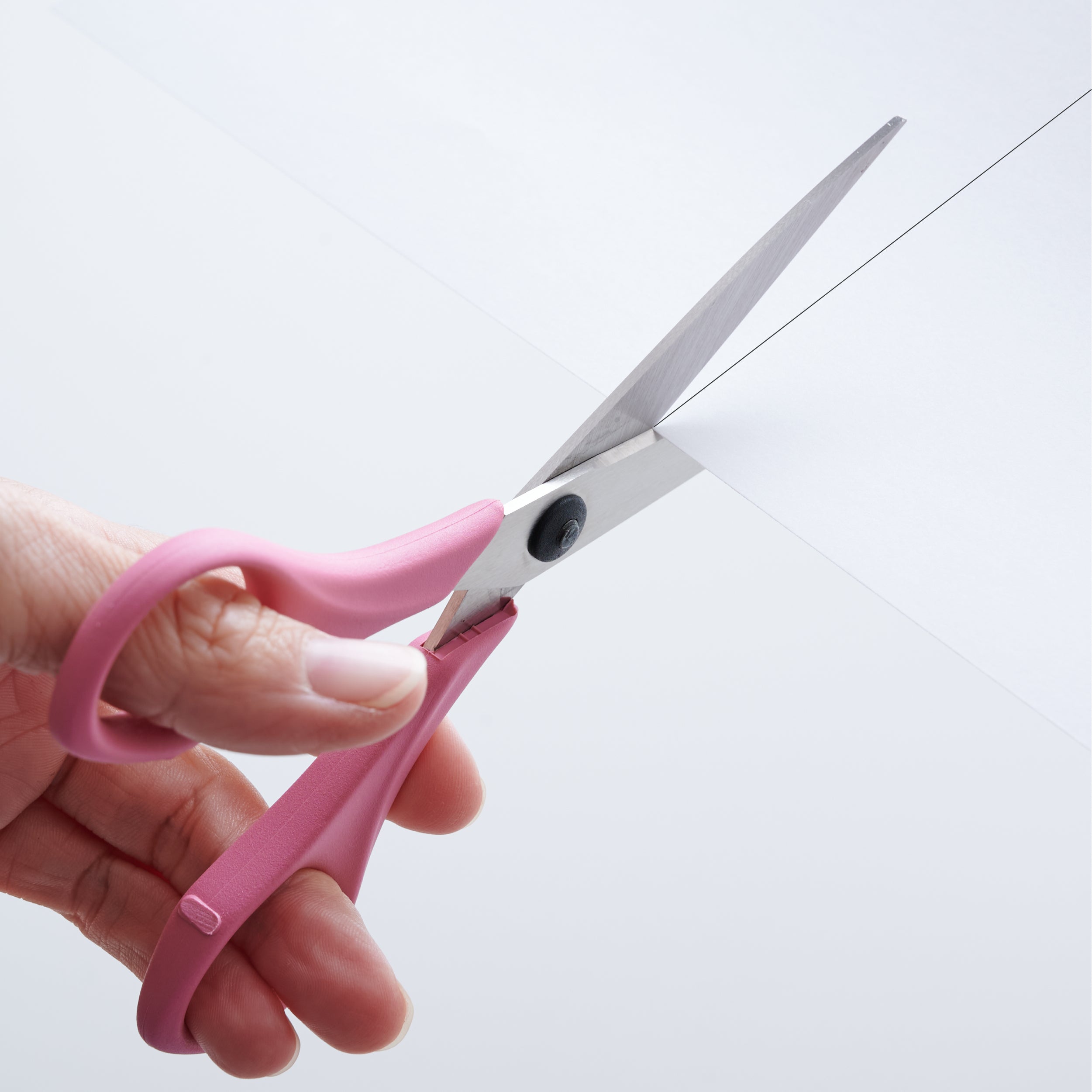 Cutting paper along the cut line with left-handed pink scissors