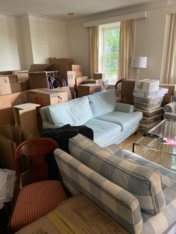 managing stress from major life transitions like moving. moving boxes, a blue couch, a blue and white check pattern sofa