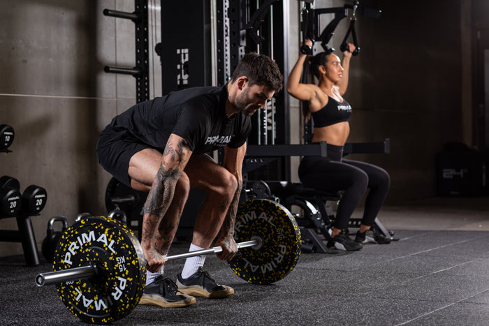 Adam Collard deadlifting while woman uses cable machine
