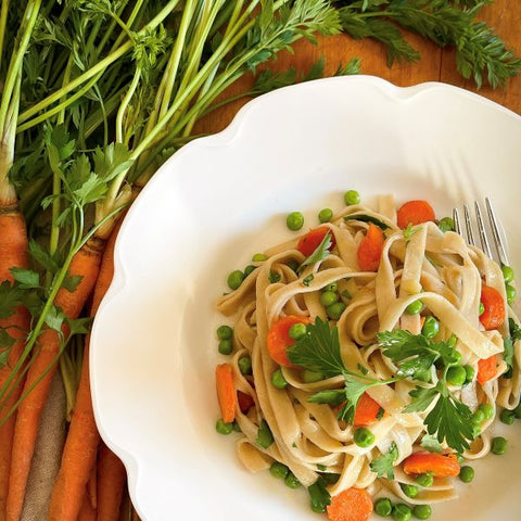 Carrot Fettuccine with carrots and springs peas on a white scalloped edge plate