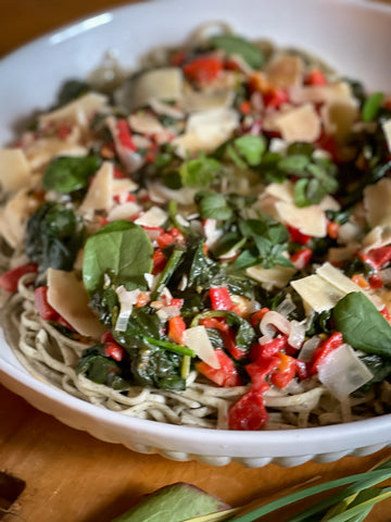 Tuscan chicken recipe with chicken breasts, spinach and roasted red peppers served in a white bowl with linguine. Date night in meal for a special restaurant-quality meal at home