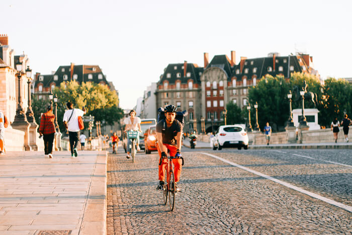 people, bikes and cars on the road