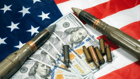 Image of large bullets and various caliber ammunition placed on top of US dollar bills and an American flag.