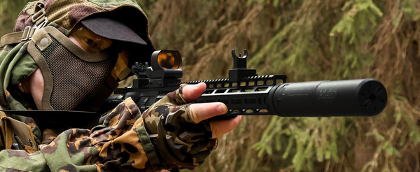 Shooter in camouflage demonstrating proper stance and alignment using iron sights on a rifle, practical for beginners learning to use iron sights.