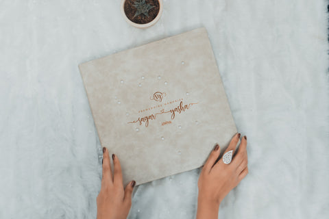 a hand holding a wedding album with gold typography.