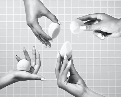 four hands holding beauty blender in black and white photo