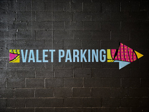 a valet parking sign arrow written on a black brick wall