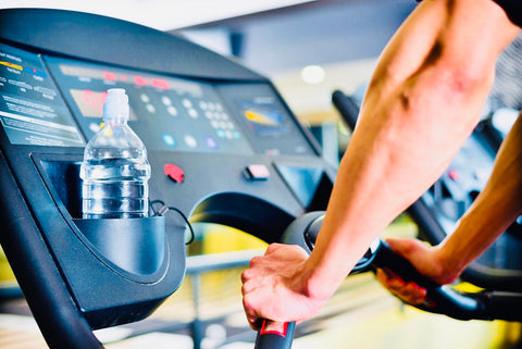 man holding hand rails on treadmill during running and looking at screen