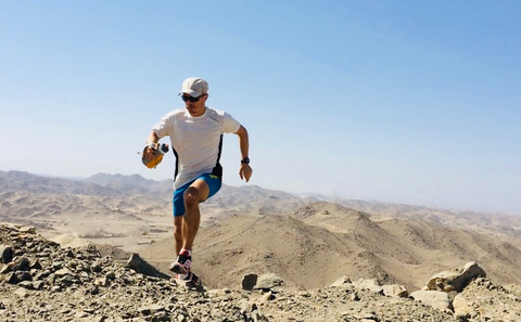 Athlete running in desert sweating and drinking active vita drink mix