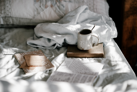 Bücher und Teetasse auf einem gemütlichen Bett
