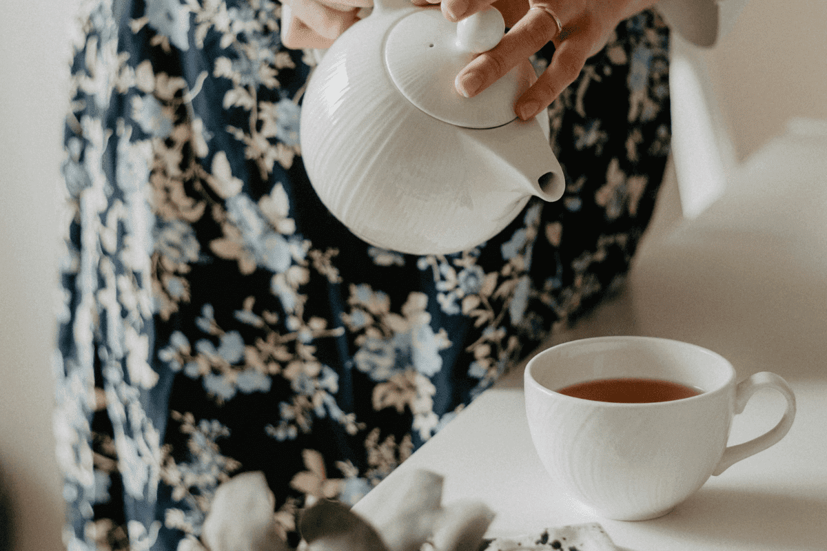 Woman pouring oolong tea into teacup from teapot