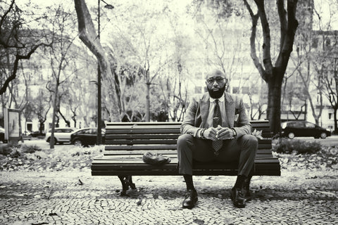 Black and White Photo of Man Sitting On Bench With Suit and Tie