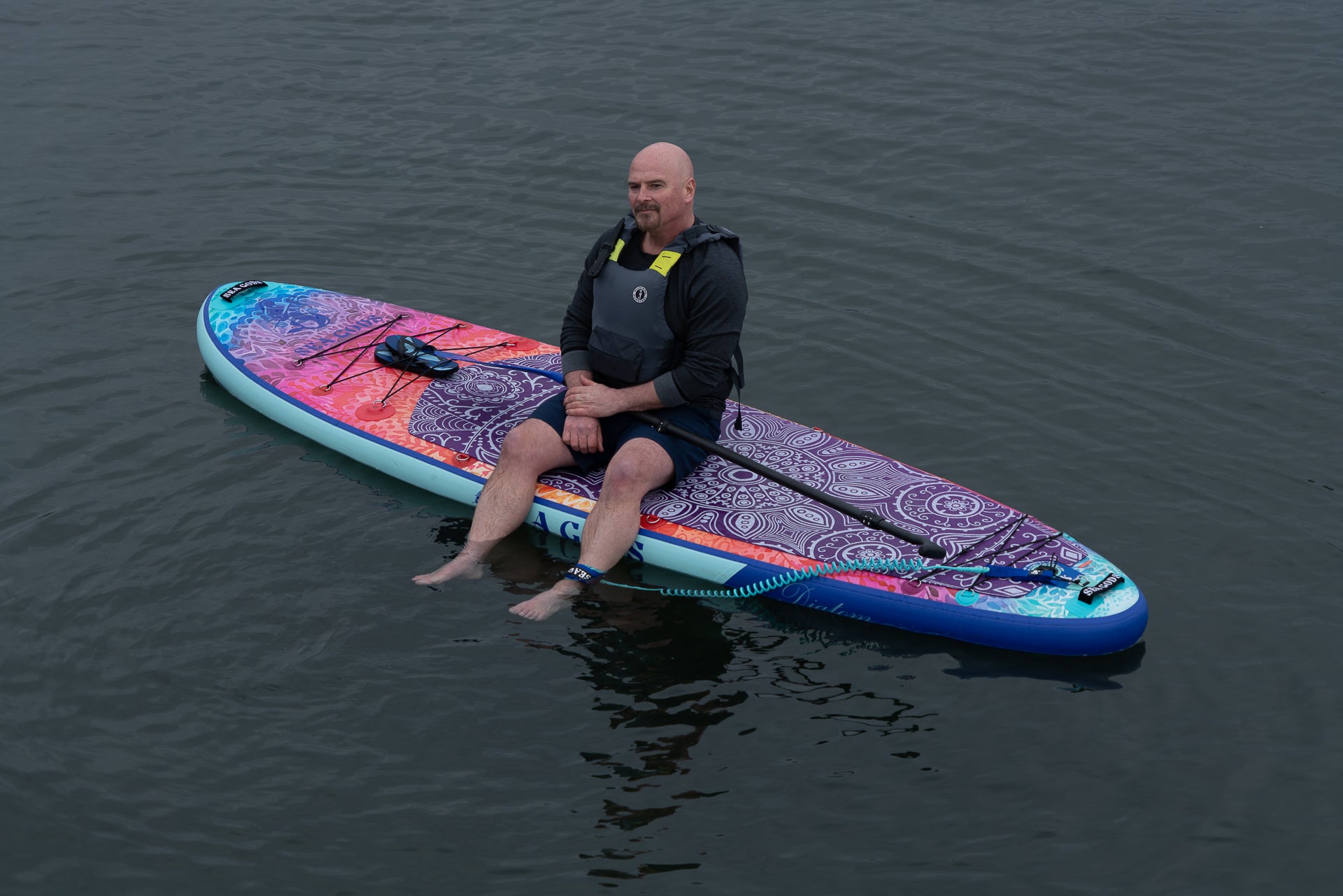 senior man sitting on the diatom ten 6 inflatable stand up paddle board