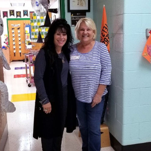 Volunteer Tina Smith standing outside a classroom with Teacher Cindy Sullivan