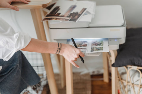 A woman using a printer and waiting for the paper to come out.