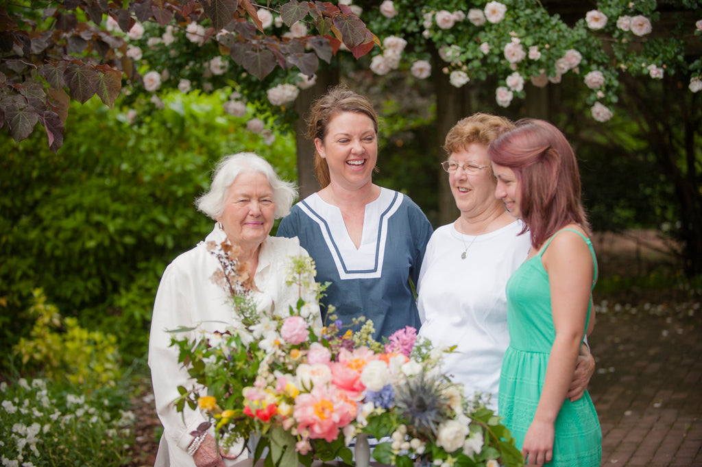 grandmother mother daughter and granddaughter family of florists with bright arrangement in a garden