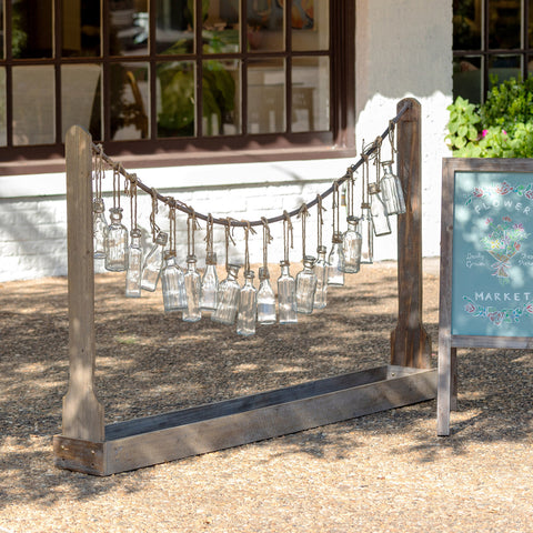 Create a festive display of freshly cut blooms for special events and gatherings with this bottle vase garland and wooden station.