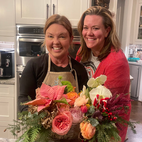 two smiling women holding luxury flower centerpiece in cumming atlanta