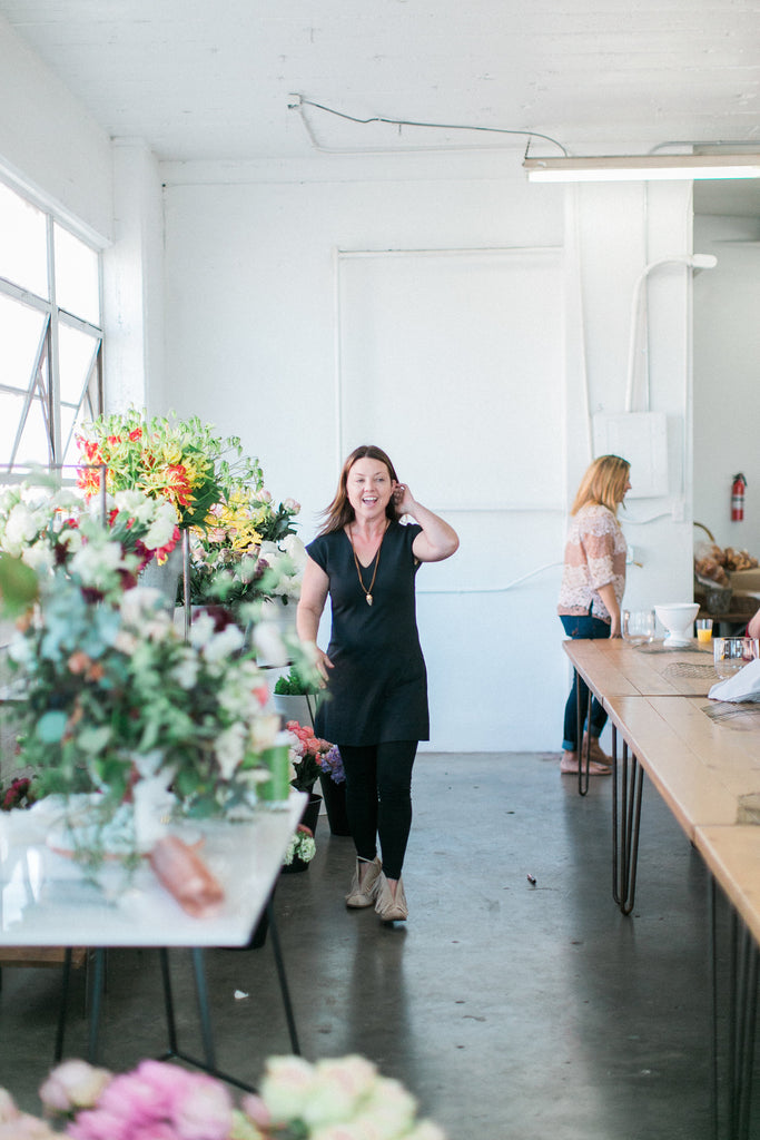 woman florist in black dress and tights white wall colorful flowers in los angles atlanta