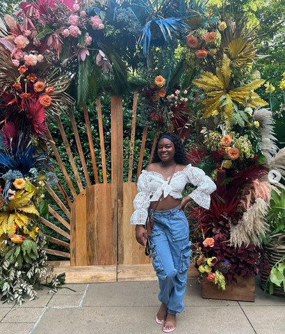 Kalex Henry in front of colorful installation by colonial house of flowers at Atlanta Botanical Garden