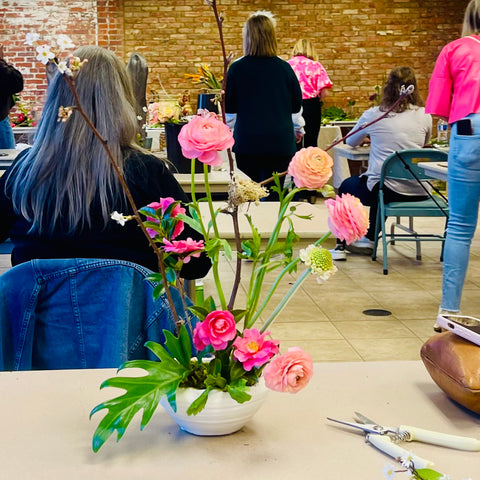 ikebana inspired floral design with pink ranunculus and green monstera leaves