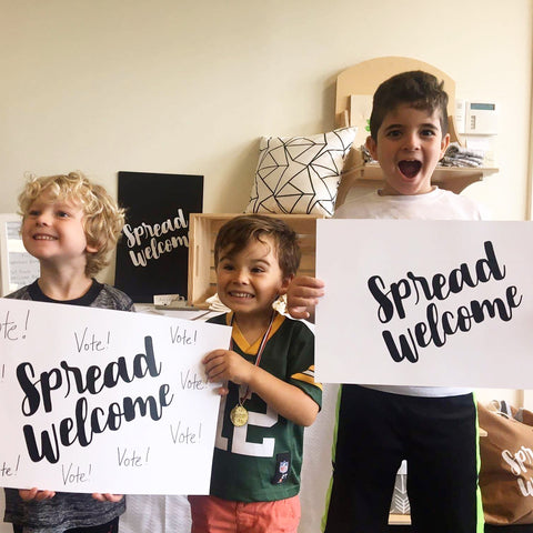 three children holding spread welcome signs