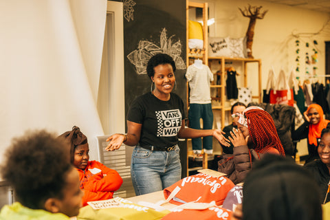 A teen girl speaking in front of a group of other teen girls, her hands outstretched