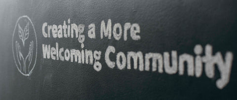 "Creating a more welcoming community" written in chalk on a black background