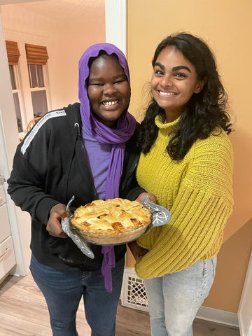 halima and hannah smiling holding a freshly baked apple pie