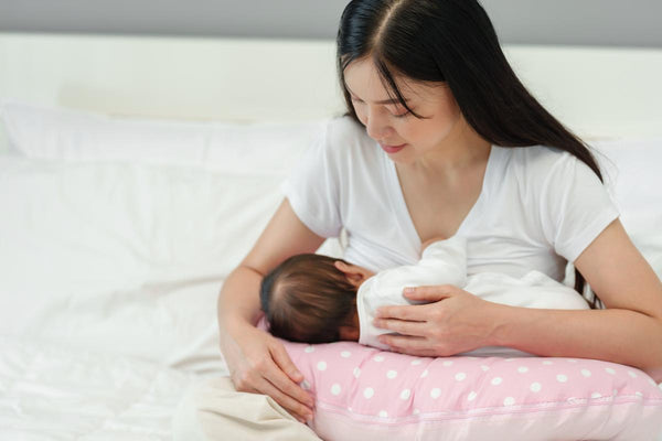 maman allaite son bébé sur un coussin