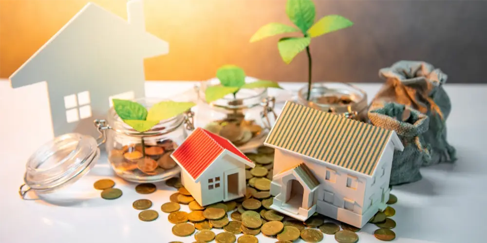 Konzeptbild für Investitionen und Einsparungen in Immobilien, mit Modellhäusern, Münzen und wachsenden Pflanzen, die finanzielles Wachstum symbolisieren
