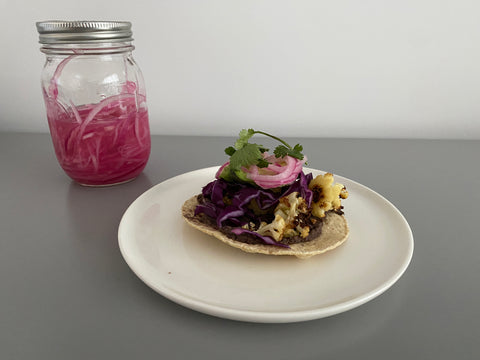 Image of a black bean taco from Beanstory with a side of pickled onions