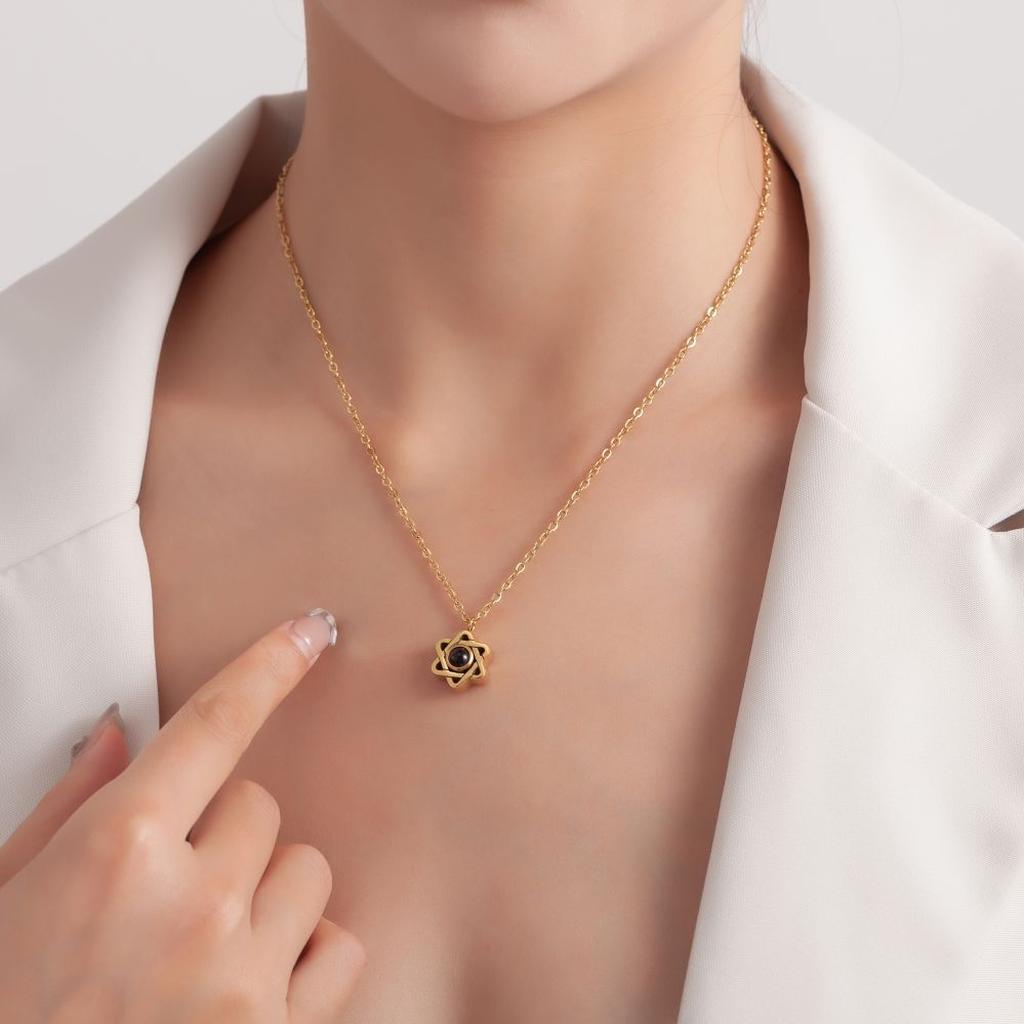 Gold six-pointed star photo projection necklace displayed on a wavy stand.