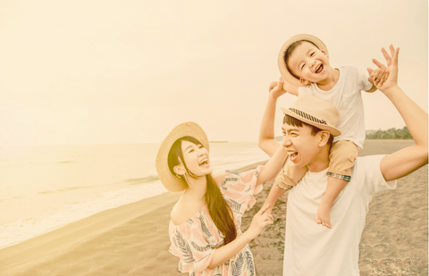 Happy asian family playing on the beach at sunset
