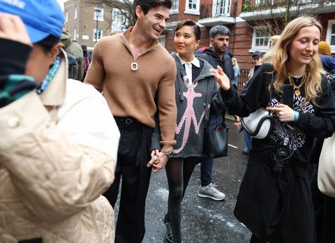 Actress Ashley Park, wearing a grey cardigan as a dress, accompanied by her boyfriend