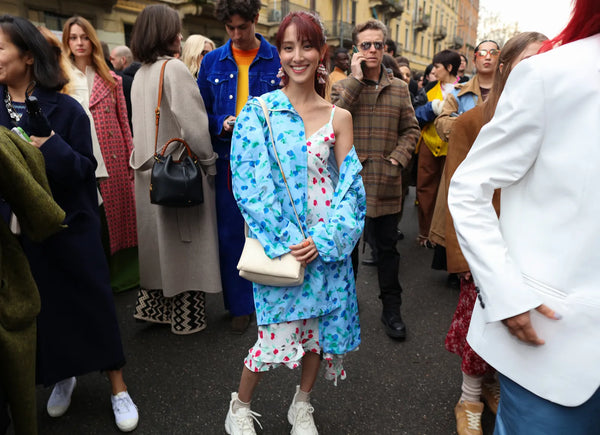 A smiling woman wearing a bright blue overcoat and a printed dress