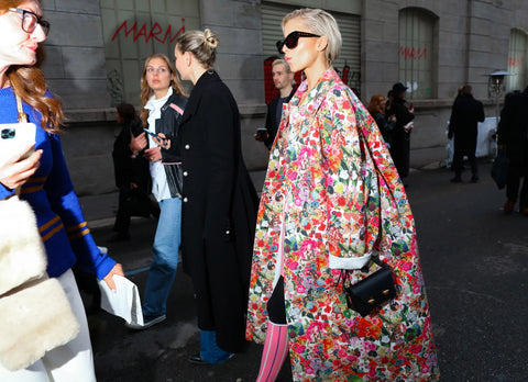 woman wearing dark sunglasses and oversized floral coat with bright pink tights