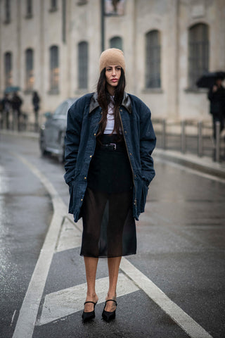 woman with long denim jacket, sheer black skirt and black hotpants underneath