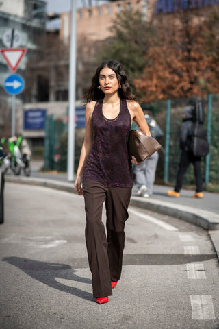 woman with metallic tank top, brown pants and red shoes