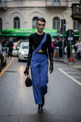 woman with black top with blue detail, blue pants and leather gloves