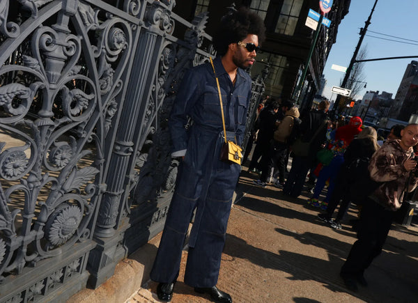 man with denim jumpsuit and yellow mini bag