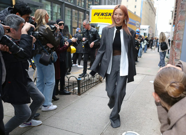 woman in grey suit with white shirt and black mesh top underneath