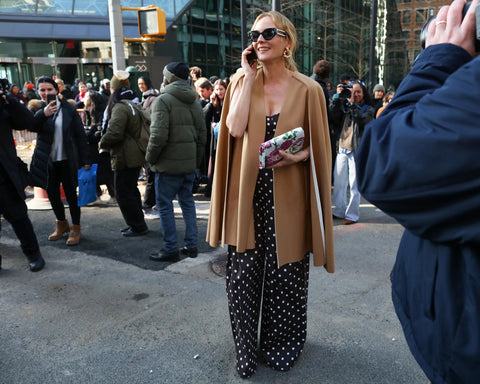 woman with polka dot jumpsuit and camel overcoat