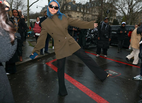 woman with blue hair, a structured olive blazer and black slacks