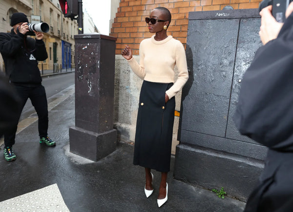 woman with ivory top, black pencil skirt with gold buttons and white pumps