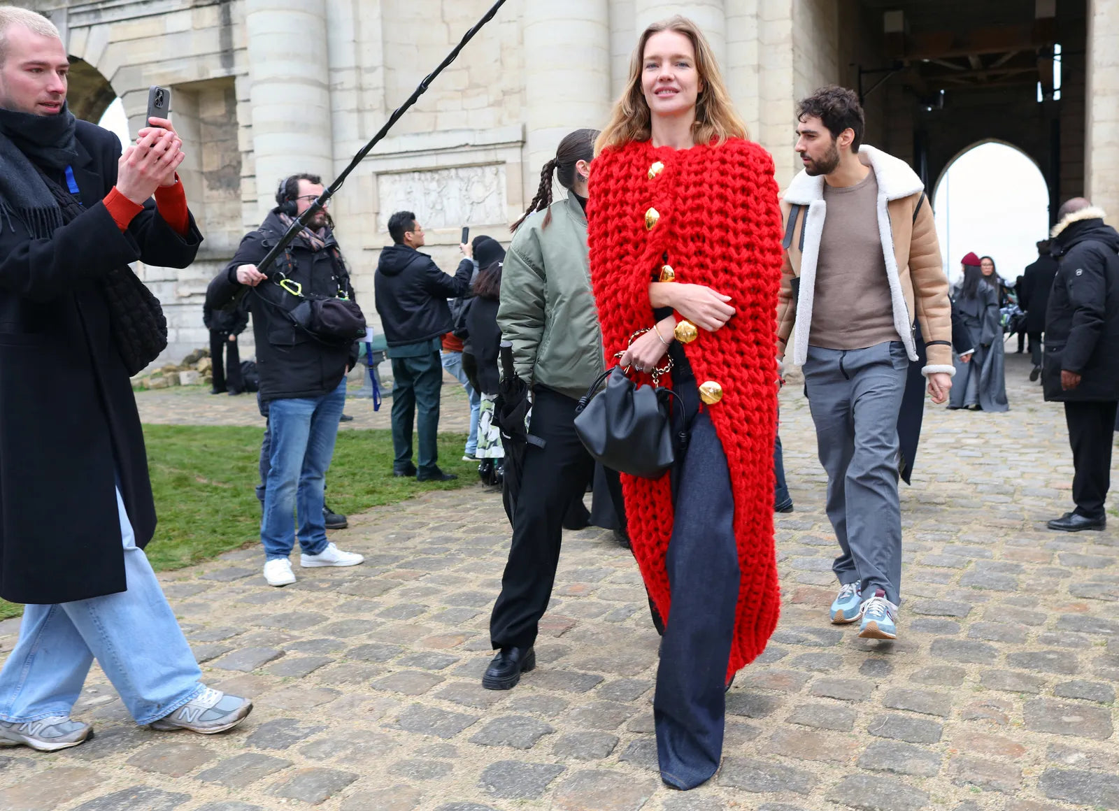Natalia Vodianova wearing a red long knitted cardigan and wide jeans